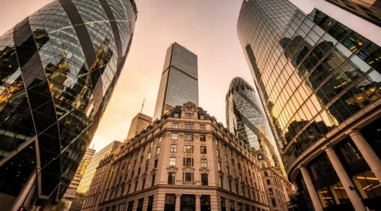Dramatic perspective view of modern glass office towers in London's financial district with golden hour lighting reflecting off facades